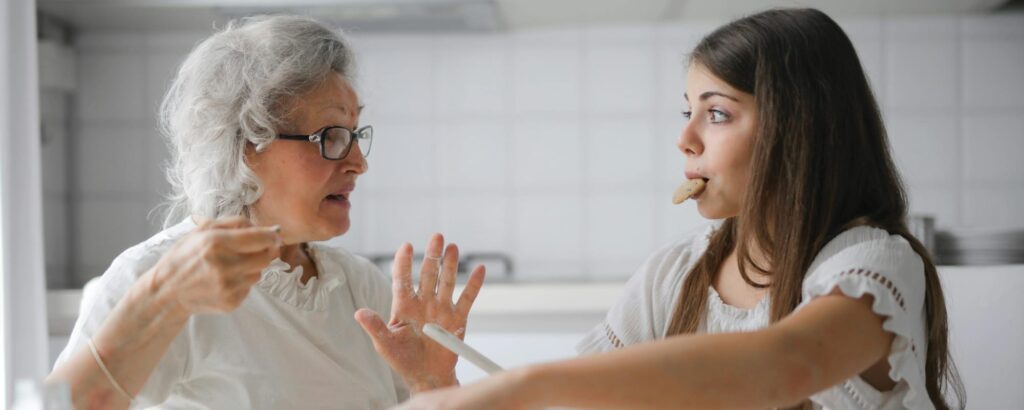 older woman with young girl with a cookie in her mouth